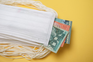 A pile of face mask with Malaysian money isolated over yellow background. Concept during Corona virus outbreak in Malaysia, shortage of face mask increase the demand in higher price.