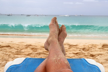 mens legs and feet resting on a beach chair portraying relaxation on holiday