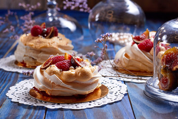 Many desserts Pavlova with raspberries and figs on old blue wooden table. Meringues on a rustic background