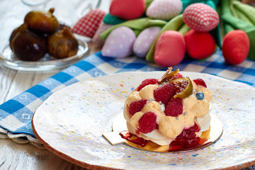 Dessert Pavlova with raspberries and figs on plate. Dessert Pavlova and figs and tulips on a rustic background.