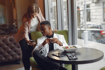Black man in a cafe. International people. Man in a black suit. Woman in a pink jacket.
