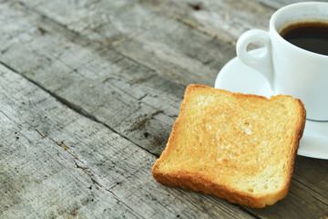 Toasted toast on a plate and a cup of espresso on a dark wooden background. English breakfast.