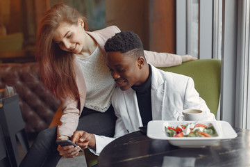 Black man in a cafe. International people. Man in a black suit. Woman in a pink jacket.