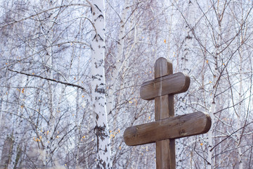 funeral christian cross on birch and sky background, front and background blurred with bokeh effect