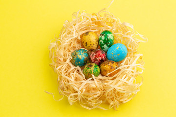 Painted easter eggs lie in a nest of shavings.