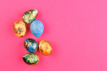 Multi-colored easter eggs lie on a pink background.