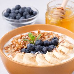 Healthy breakfast with granola, bananas, blueberry and honey closeup