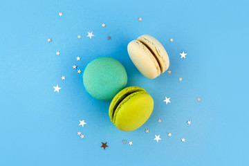 Colorful macaroon flat lay on bright blue background with confetti. French delicious dessert