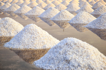 Sea salt pile pyramid ready for harvest in salt farm at sunrise. Sea salt is salt that is produced by the evaporation of seawater. Used as a seasoning in foods, cooking, cosmetics and for preserving f