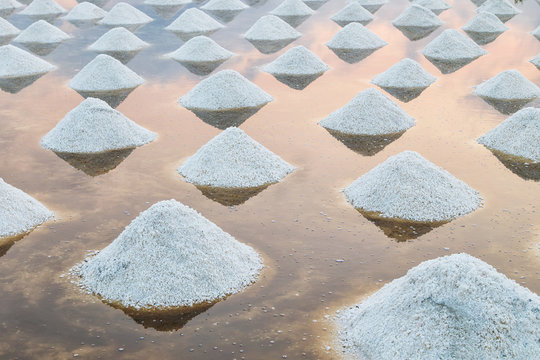 Sea salt pile pyramid ready for harvest in salt farm at sunrise. Sea salt is salt that is produced by the evaporation of seawater. Used as a seasoning in foods, cooking, cosmetics and for preserving f
