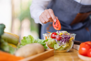 Closeup image of a female chef cooking a fresh mixed vegetables salad in kitchen