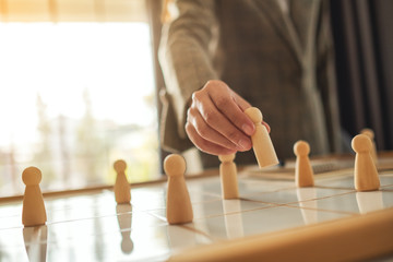 Businesswoman leader choosing wooden people from a group of employees on a planning board