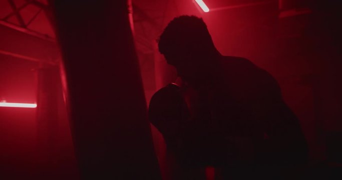 Male Boxer training boxing in red dark gym