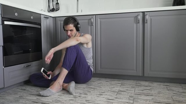 Handsome sad man sitting on floor and listening music