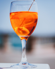 Glass of Aperol Spritz cocktail in a sunny setting with a blue sky