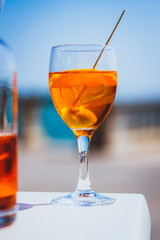 Glass of Aperol Spritz cocktail in a sunny setting with a blue sky