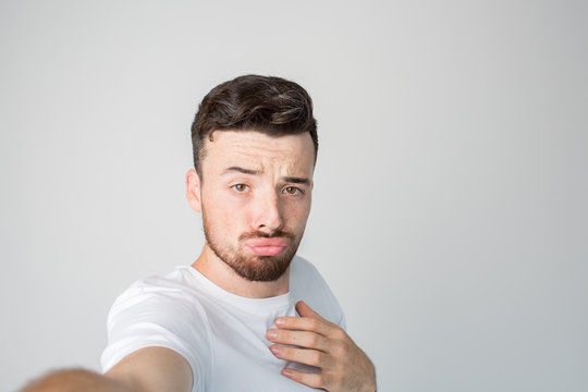 Young man isolated over background. Brutal mysterious guy with strange fasial expression posing on camera. Take selfie alone in studio. Love himself.