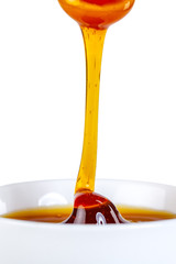 honey dripping from ceramic spoon to ceramic bowl