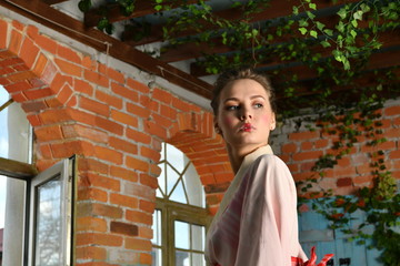 girl in japanese kimono posing on the background of flowering plants