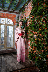 Fototapeta na wymiar girl in japanese kimono posing on the background of flowering plants
