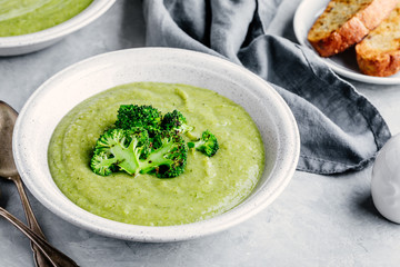 Homemade broccoli cream soup in white bowl with toasts