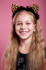 Close-up of little smiling girl in cat ears on pink background