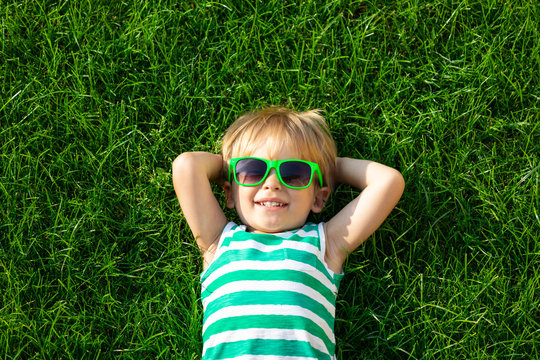 Happy child lying on spring green grass