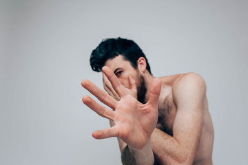 Young man isolated over background. Posing on camera alone and with naked chest. Show hand. Mental disease and stressful period. Confused guy posing alone.