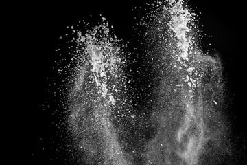 Burst of white powder with flour and sugar creating a beautiful pattern isolated on black background
