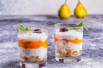 Homemade yogurt with persimmon jam, granola and chia grains in glasses , pears on blurred...