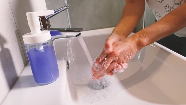 Coronavirus pandemic prevention wash hands with soap. Woman washing her hands with purple soap.