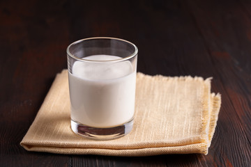 fermented drink kefir in a glass glass on bworn wooden background.