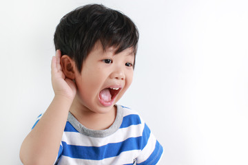 Portrait of little Asian boy with hand by ear against white background.
