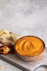 Almogrote , cheese paste form La Gomera, Canary Islands in wooden bowl on cut board with hard goat cheese, peppers  and garlic.Close up.Copy space