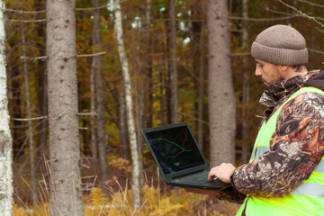 Ecologist works in the forest on the computer. Observation of forest development. Afforestation and...