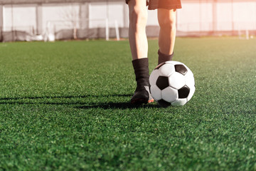 Young boy soccer player and ball close-up on a green football field. Sports activity of children concept. Kids football school. Tournament. Sports background, copy space.