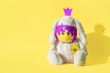 Rabbit in a medical creative mask on a yellow background with copy space. Shadow of a coronovirus molecule. Concept of coronovirus infection, quarantine. Easter quarantine, self-isolation..Stay  home