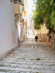 Fototapeta na wymiar Old man walks down from steps in historical town of Palma de Mallorca