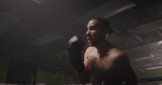 Male shadow boxing in dark gym