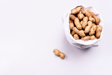 Peanuts in shell in canvas bag on white background. Selective focus. Copy space