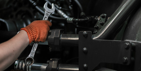 Banner with close up view of hydraulic pipes of heavy industry machine and hands of mechanic. Low...