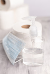 Background for the disinfection of coronavirus. Sanitizer, protective medical mask, rolls of toilet paper. Compliance with disinfection, cleanliness, hand wet. Vertical frame.