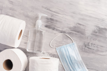 Flat lay. Banner, Background for disinfection of a coronavirus. Sanitizer, protective medical mask, toilet paper rolls. Compliance with disinfection, cleanliness, hand wet, Inscription space.