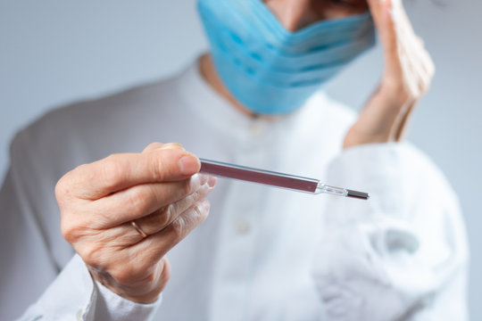 Coronavirus quarantine and Air pollution pm2.5 concept. Old sick woman wearing respirator mask for protect holds thermometer. Wuhan, China epidemic virus symptoms background.