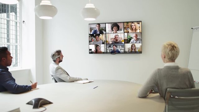 Group Using Video Conferencing technology in office for video call with colleagues abroad