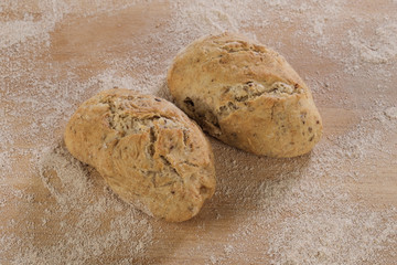 Zwei traditionell selbst gebackenes Brötchen auf Brett mit Mehl in einer Bäckerei