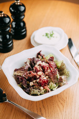 Restaurant serving salad with cheese, tomatoes and herbs. Fresh vegetable salad on a white plate.