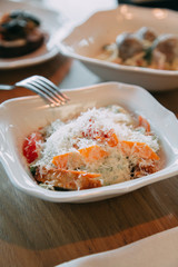 Restaurant serving salad with cheese, tomatoes and herbs. Fresh vegetable salad on a white plate.