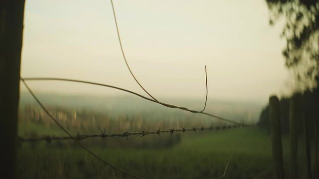 A beautiful cinematic view of a rustic barbed wire fence in the countryside of Tandle Hills, England in anamorphic format.
