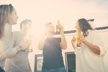 Happy carefree friends drinking beer, dancing and having fun on outdoor terrace. Young men and women in casual meeting outside. Party outside concept